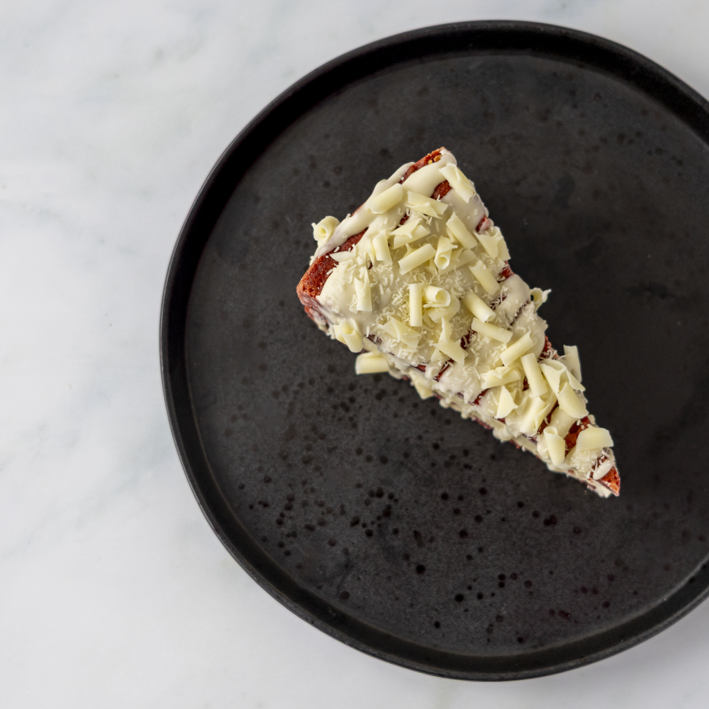 Overhead view of Red Velvet Cookie Pie Slice on black plate with white chocolate topping