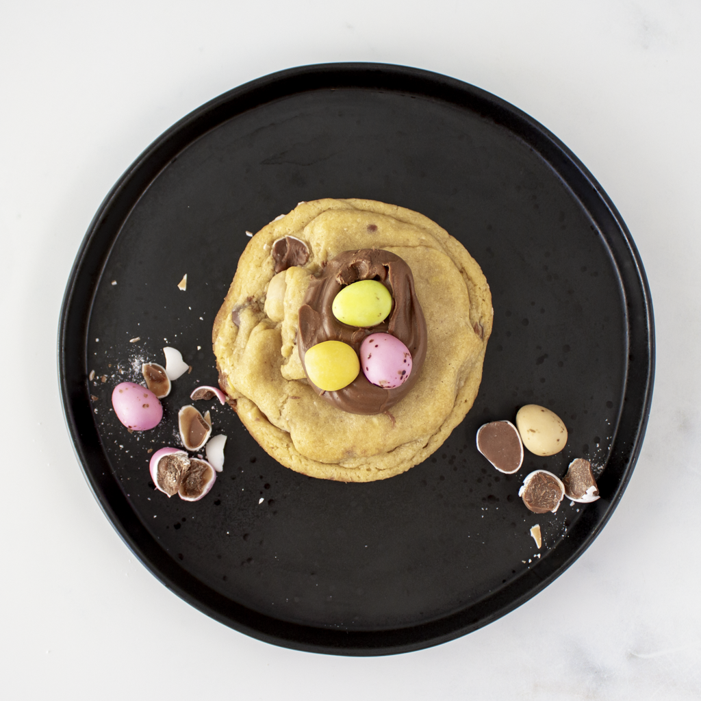 Cookie with chocolate and chocolate mini eggs on a black plate, perfect for Easter gift and Easter decoration