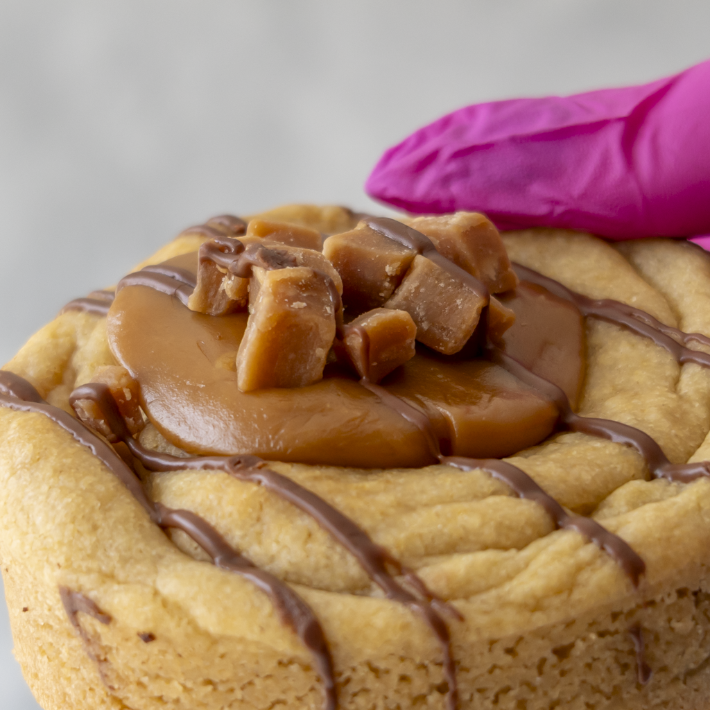Close-up of DoughGirl Caramel Fudge Cookie with golden caramel and fudge pieces