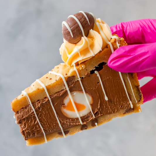 DoughGirl Cookie Pie Slice With Creme Egg hold by a pink gloved hand