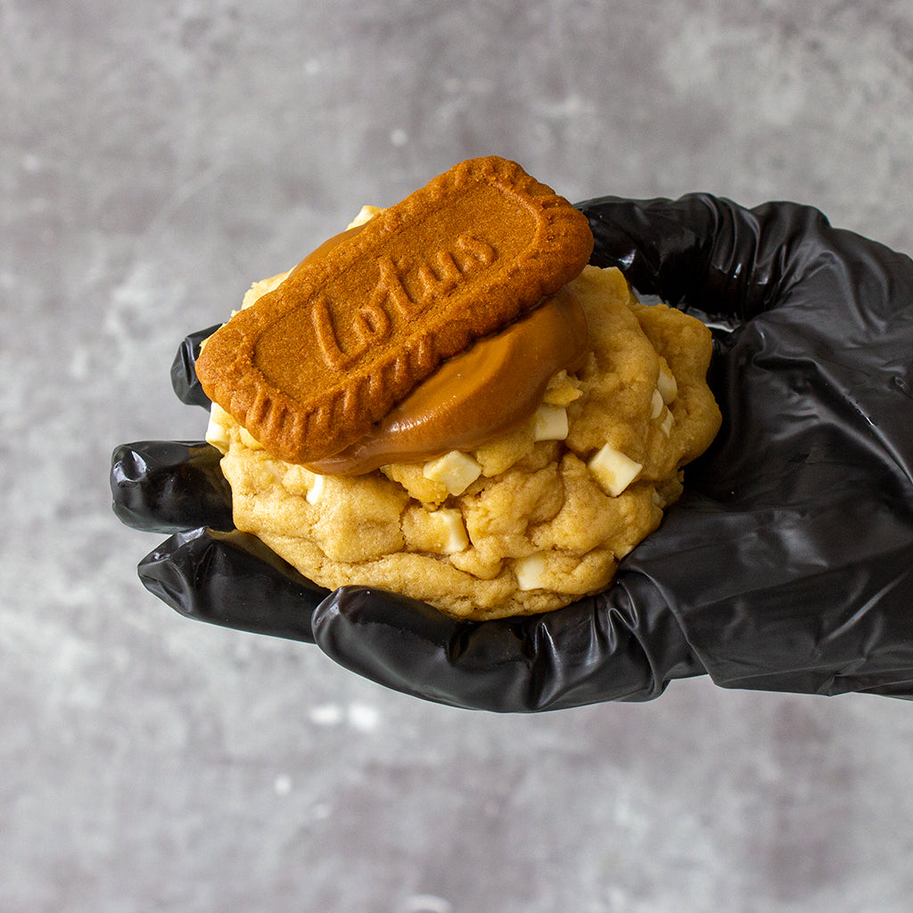 DoughGirl chunky cookie topped with Biscoff biscuit held by hand for freezing and reheating guide