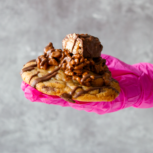 DoughGirl Stuffed Deluxe Cookie with Lion Bar hold by a pink gloved hand
