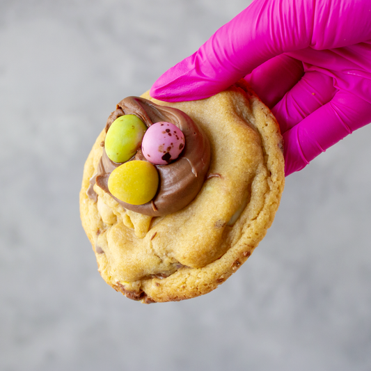 DoughGirl The Mini Egg Deluxe Cookie held by a pink gloved hand