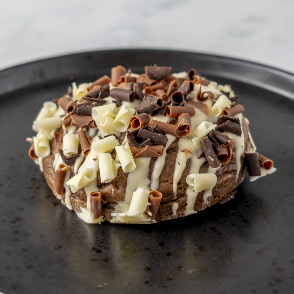 Chocolate cookie topped with white chocolate drizzle and chocolate curls