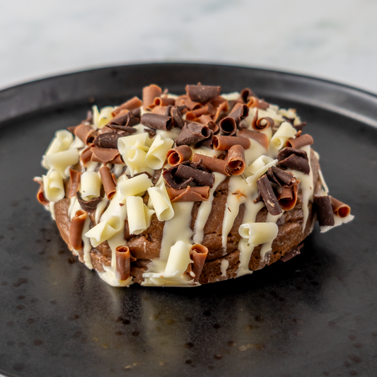 Chocolate cookie topped with white chocolate drizzle and chocolate curls