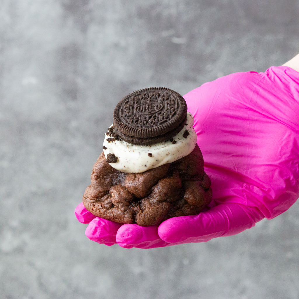 DoughGirl chocolate NYC-style cookie topped with cream and Oreo biscuit held by hand