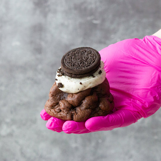 DoughGirl chocolate NYC-style cookie topped with cream and Oreo biscuit held by hand