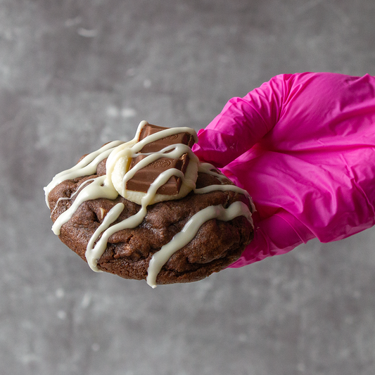 DoughGirl chocolate cookie with white chocolate drizzle held by hand