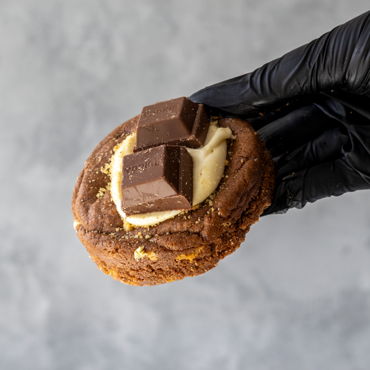 DoughGirl Deluxe Cookie with Yorkie, Biscuit & Brownie Bar hold by black gloved hand