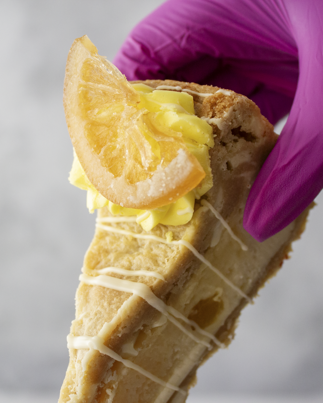 DoughGirl lemon cookie pie slice with white chocolate drizzle held by hand