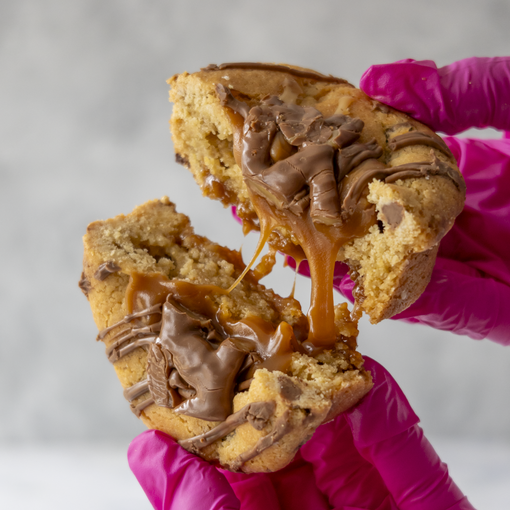 Gooey caramel-filled cookie pulled apart by hand