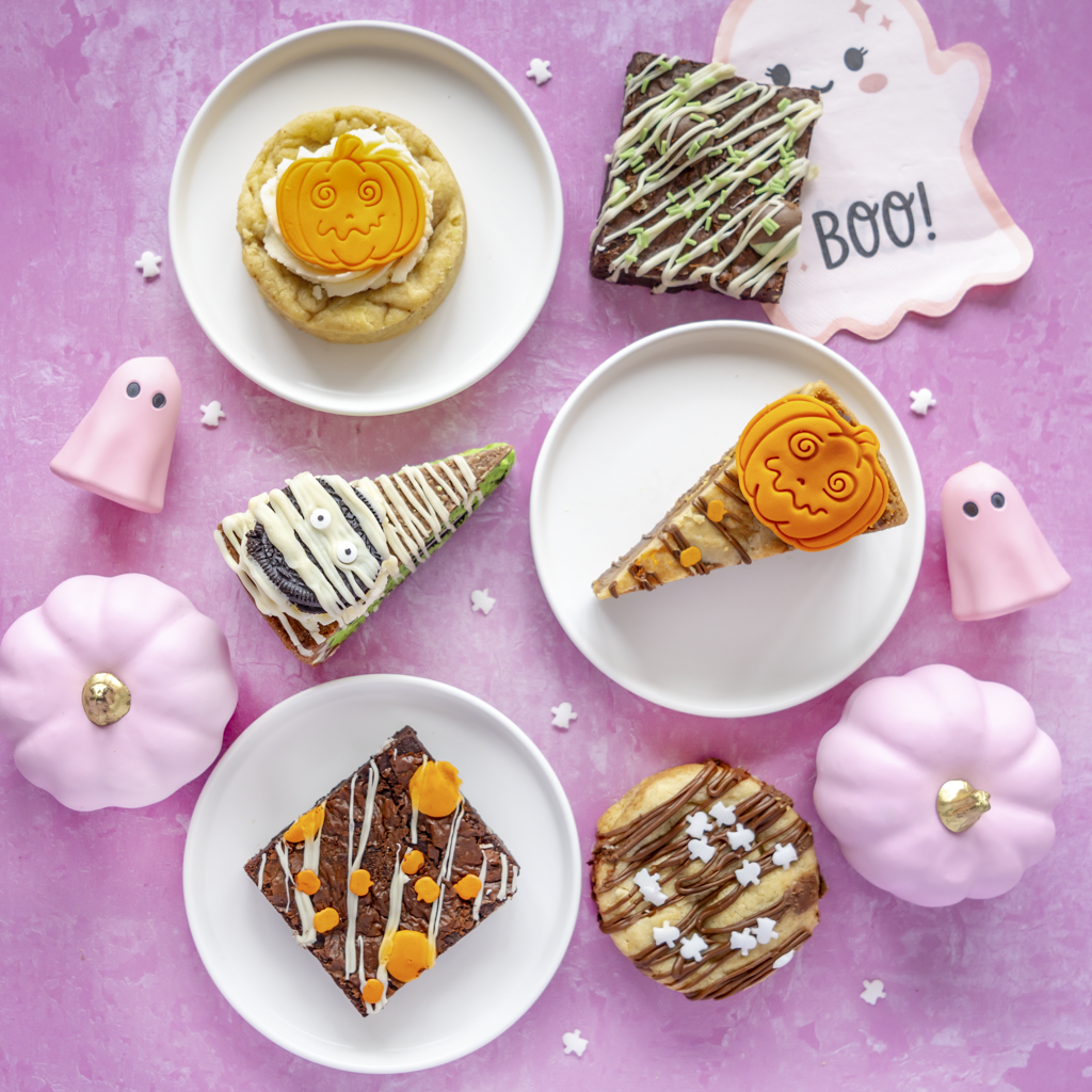 Halloween treat selection with Halloween cookies, pumpkin cookie pie slices and autumn brownie slabs, styled with pink pumpkins, ghosts and BOO decorations.
