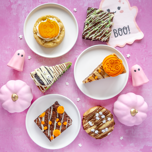 Halloween treat selection with Halloween cookies, pumpkin cookie pie slices and autumn brownie slabs, styled with pink pumpkins, ghosts and BOO decorations.