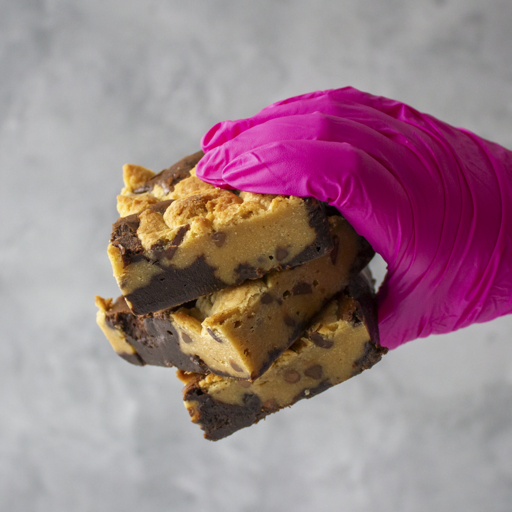 Hand wearing a pink glove holding a stack of Classic Brookie Slabs against a gray background