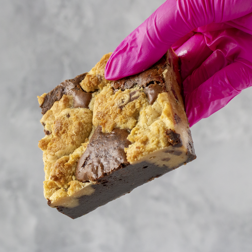 DoughGirl Classic Brookie Slab held by a hand wearing a pink glove on a gray background