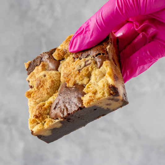 DoughGirl Classic Brookie Slab held by a hand wearing a pink glove on a gray background