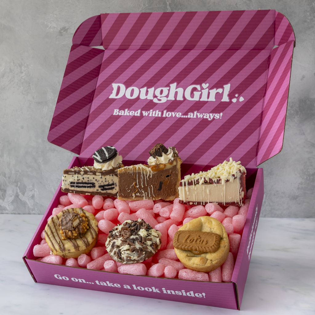 A pink striped DoughGirl baking gift box filled with assorted cookies, cookie pie slices shown on a light gray background.