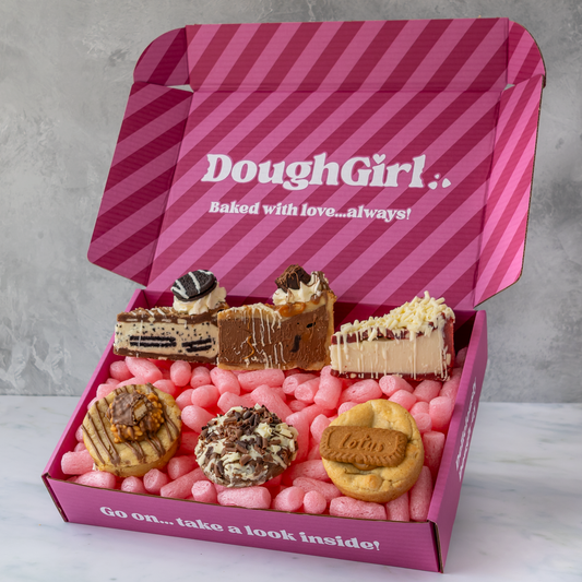 A pink striped DoughGirl baking gift box filled with assorted cookies, cookie pie slices shown on a light gray background.