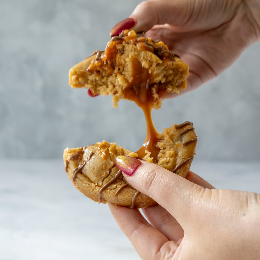 Two hands holding a Lion Bar Deluxe Cookie with a blurred background