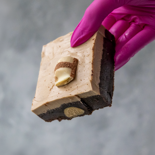 Bueno Brownie Slab held by a hand wearing a purple glove against a gray background