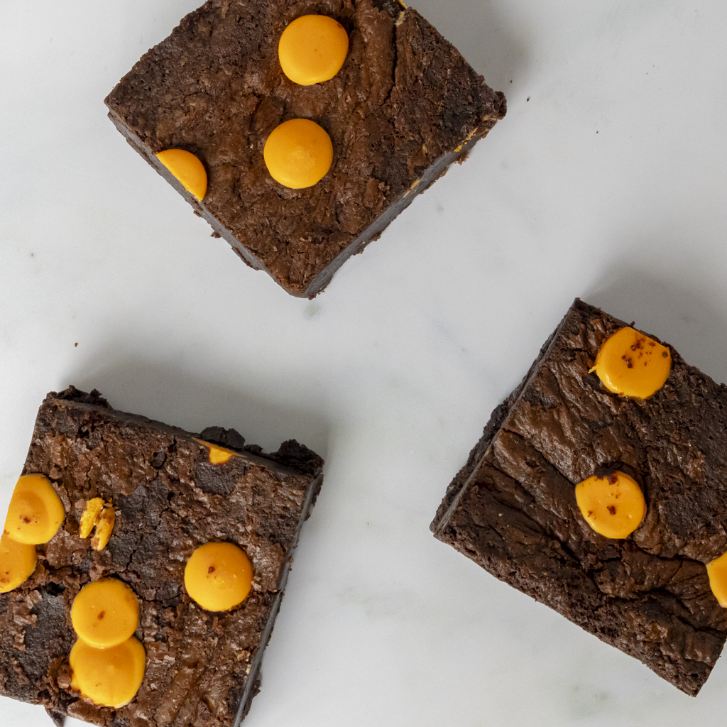 Three Chocolate Orange Brownie Slab with orange sweets on a white surface