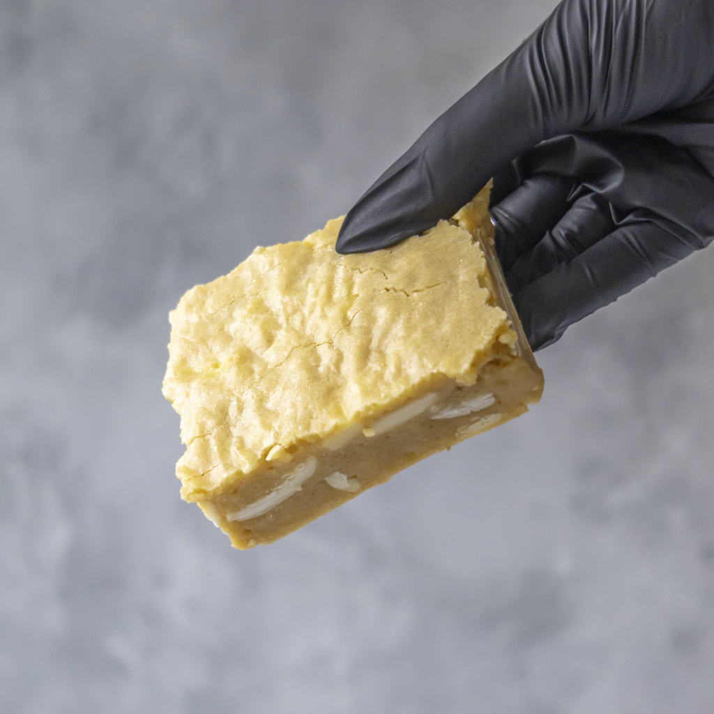 Hand wearing a black glove holding a Classic Brookie Slab with white filling against a gray background