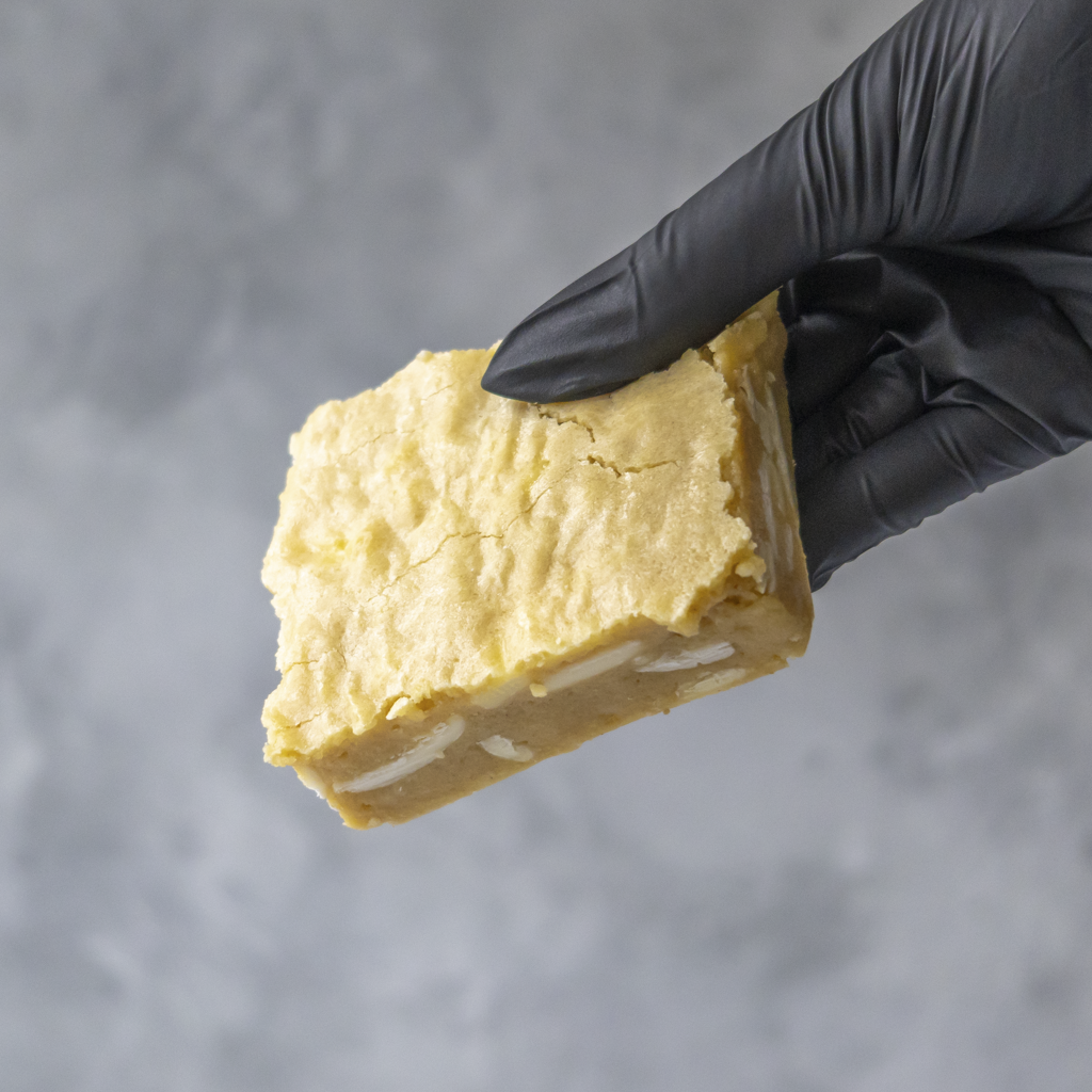 Hand wearing a black glove holding a Classic Blondie Slab against a gray background