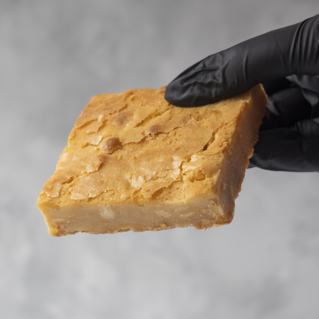 Classic Blondie Slab held in black glove showing soft vanilla blondie centre