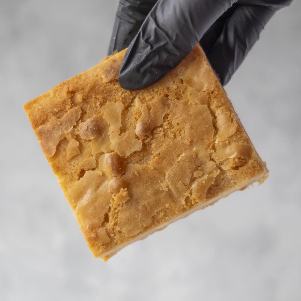 Classic Blondie Slab held in black glove showing thick gooey blondie texture