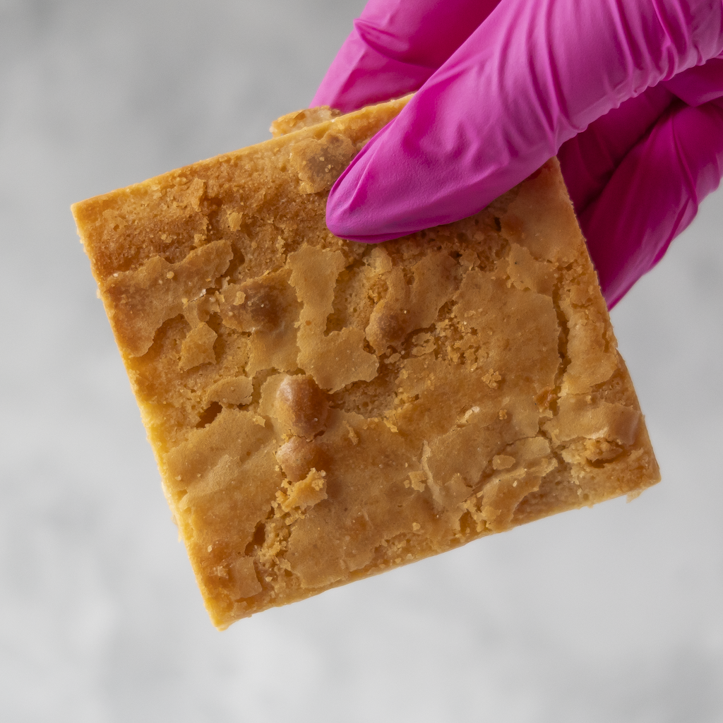 DoughGirl Classic Blondie Slab held in pink glove with white chocolate chunks