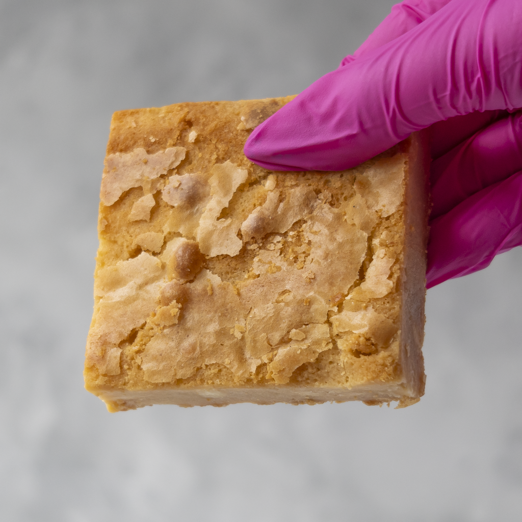 DoughGirl Classic Blondie Slab held in pink glove with golden bakery-style top