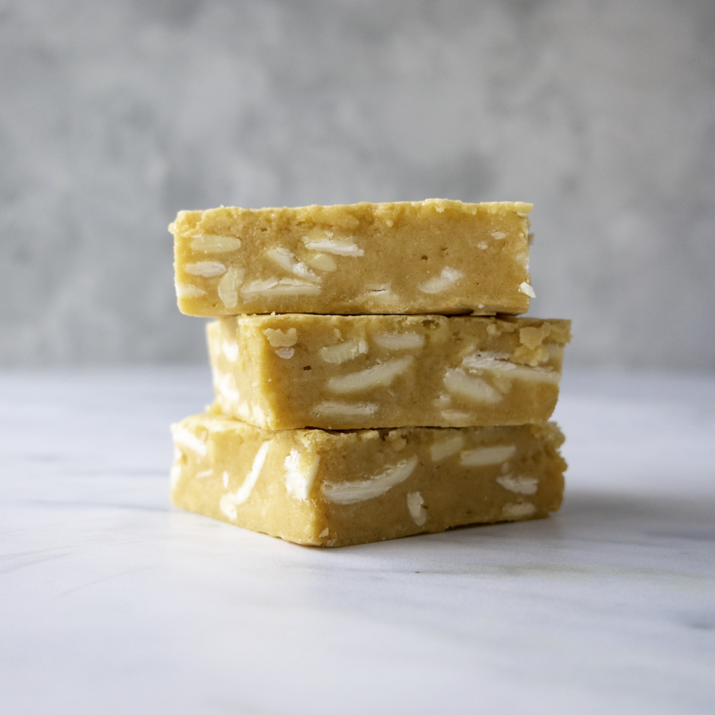 Stack of three Classic Blondie Slabs by DoughGirl with white chocolate chunks on a light gray background