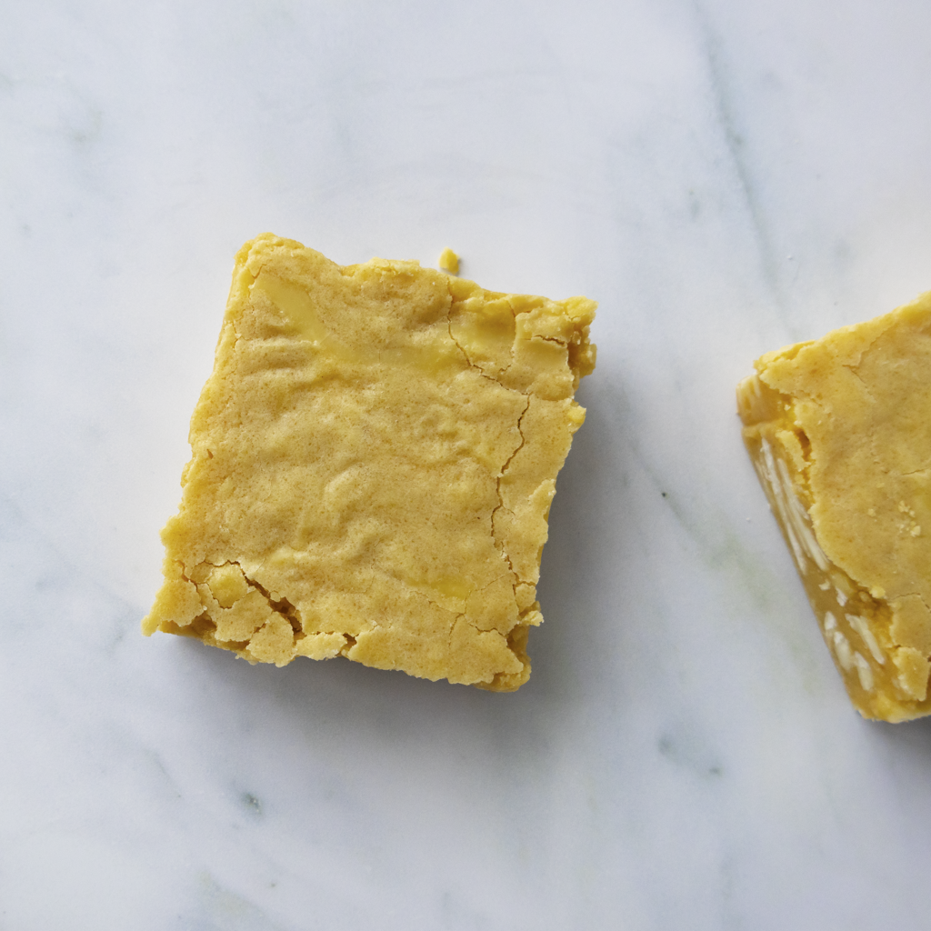 Two square blondie slabs made with with real vanilla and golden brown sugar on a marble surface