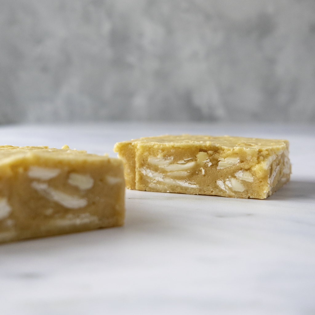 Close-up of two pieces of classic blondie slabs on a light gray surface with a blurred gray background.