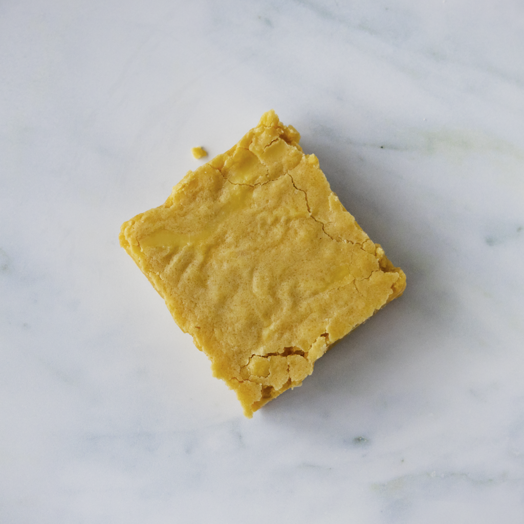 Square piece of yellow blondie slab on a marble surface