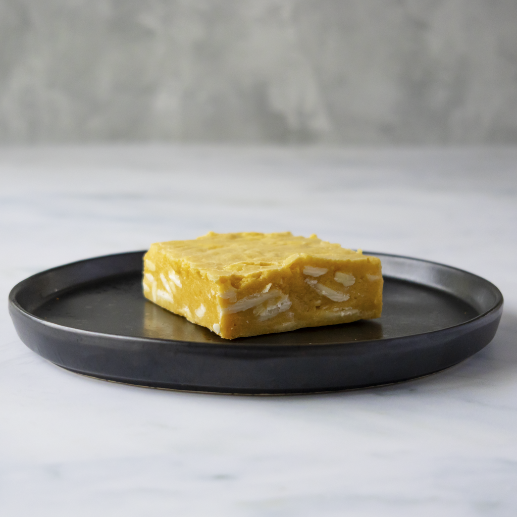 Square brookie generously loaded with creamy white chocolate chunks on a black plate with a gray background