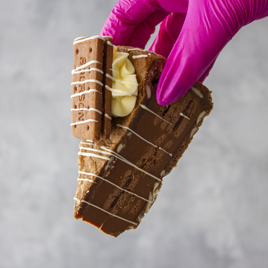 DoughGirl Bourbon Biscuit Cookie Pie Slice held in pink glove with Bourbon biscuit topping
