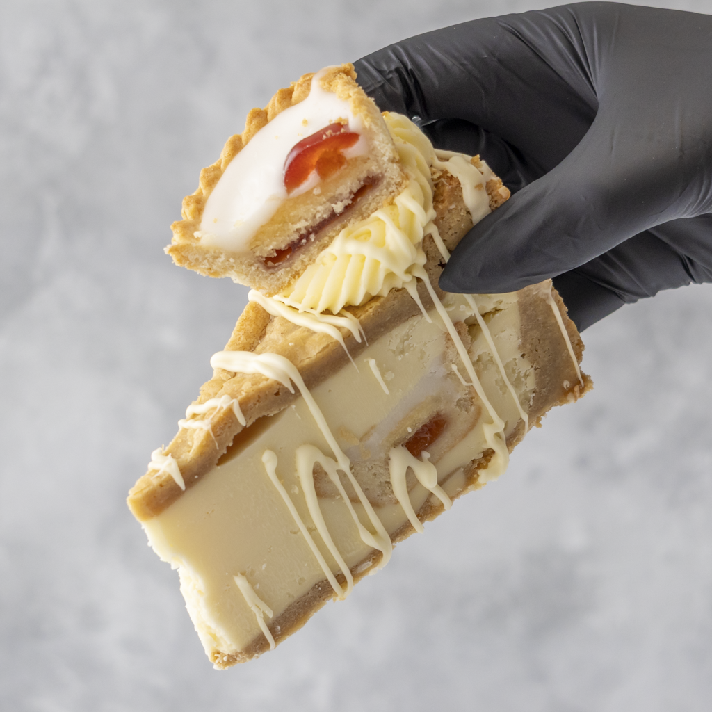 Hand holding a Cherry Bakewell Cookie Pie by DoughGirl with white chocolate, against a gray background