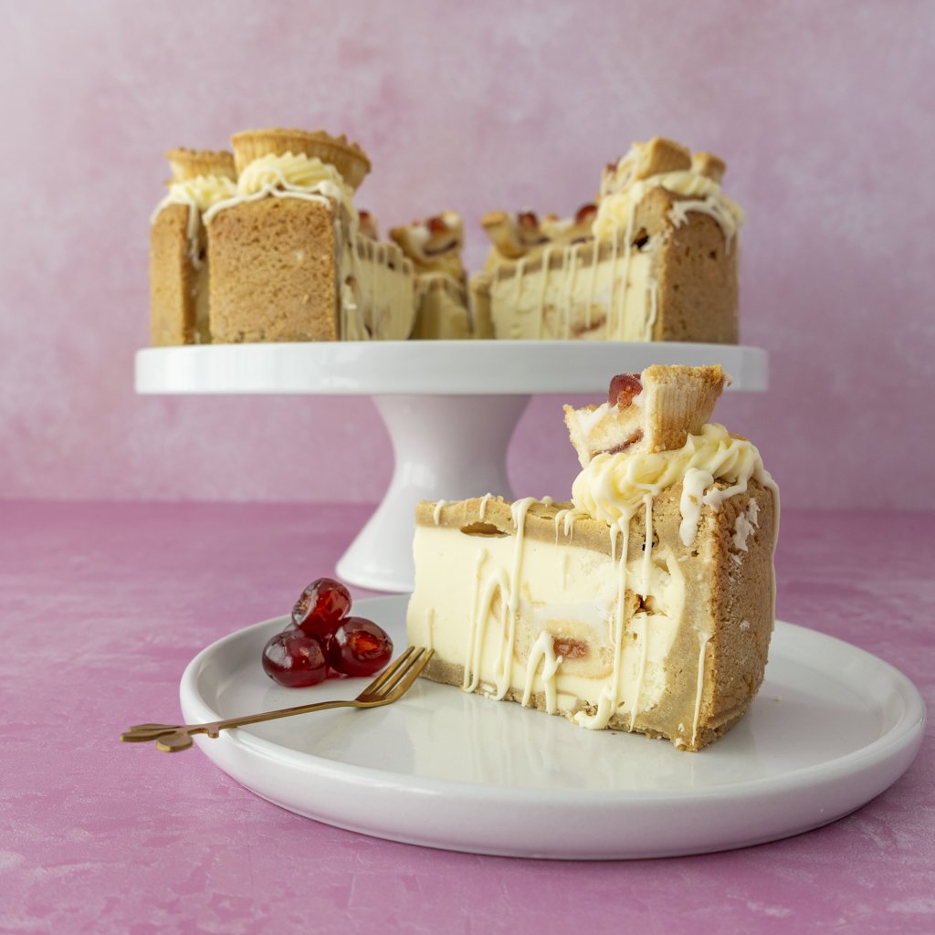 Full limited edition Cherry Bakewell Cookie Pie with a slice on a plate against a pink background