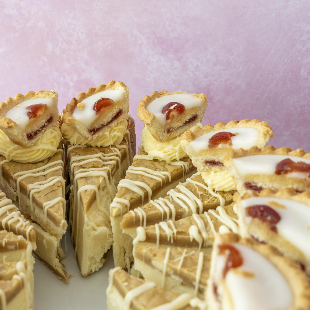 Sliced cake with cream and jam on a pink background