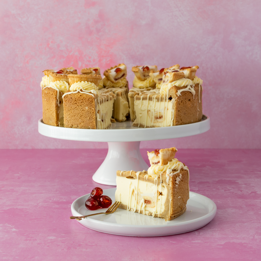 DoughGirl 12-Slice Cherry Bakewell Cookie Pie on a white stand with a pink background