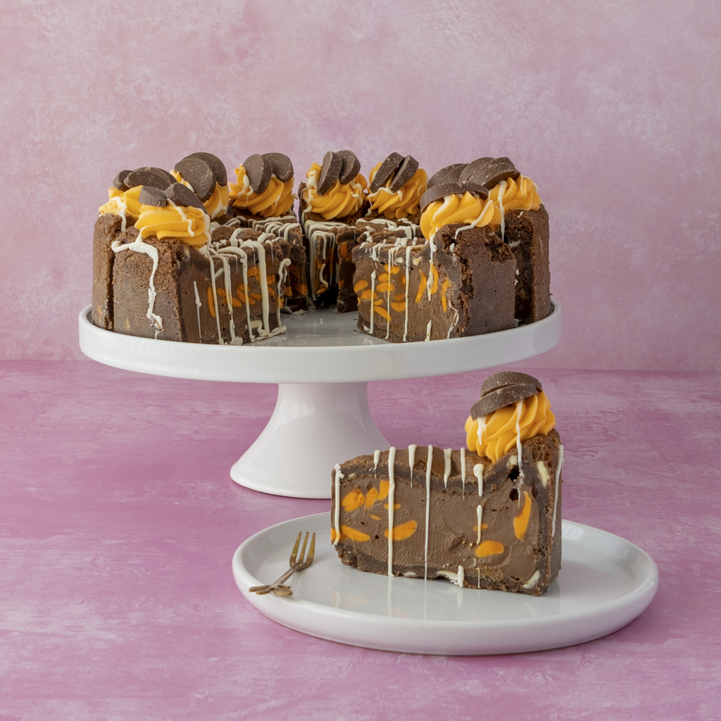 DoughGirl Full Chocolate Orange Cookie Pie with orange filling on a white cake stand against a pink background
