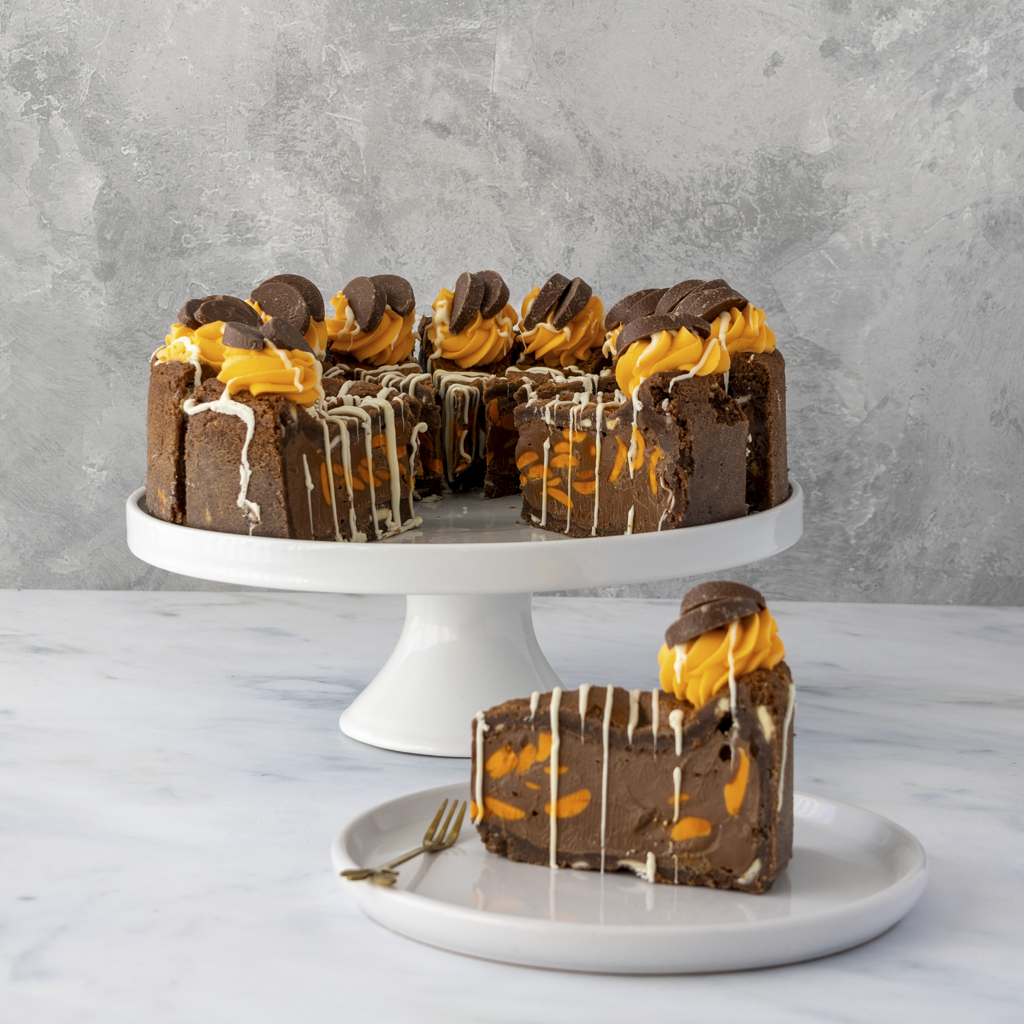 Full chocolate cookie pie with orange chocolate filling on a white cake stand against a gray background