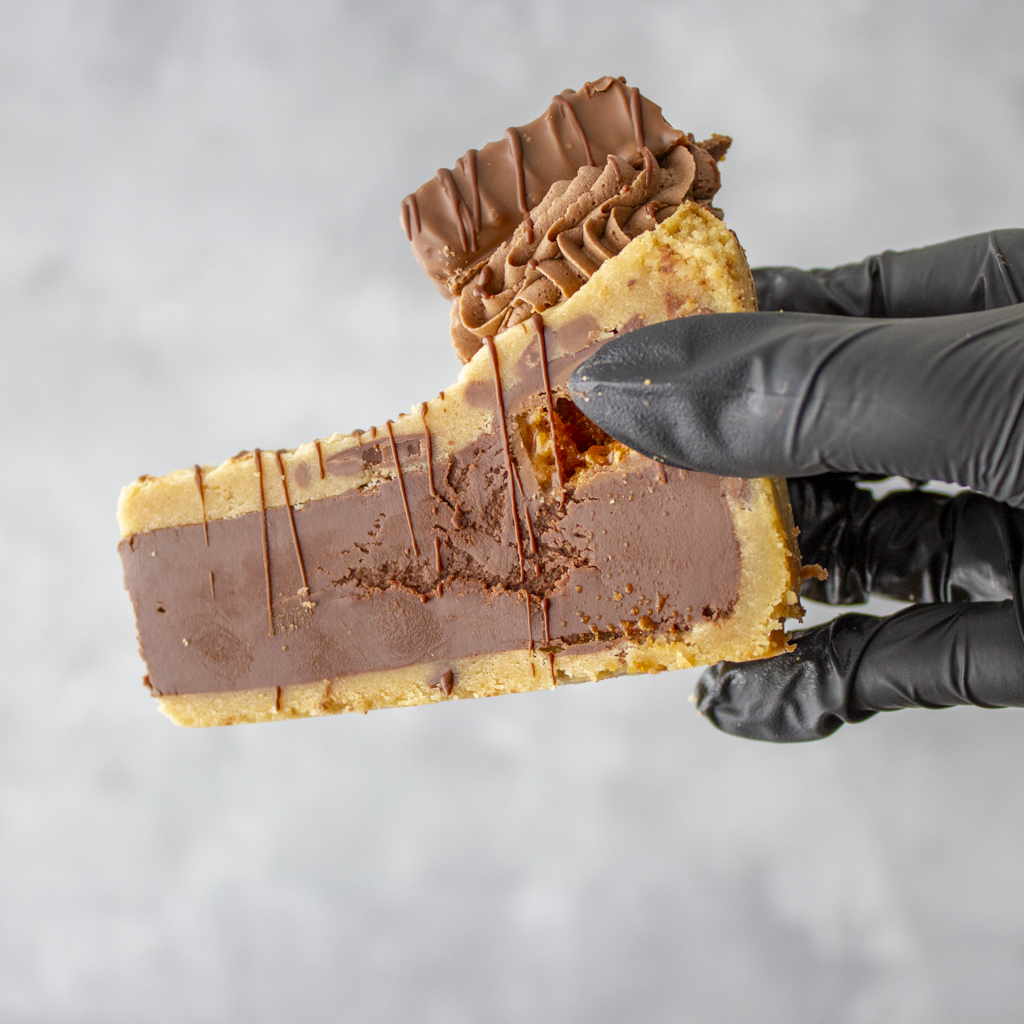Cookie Pie Slice with Crunchie held in black glove showing thick chocolate centre