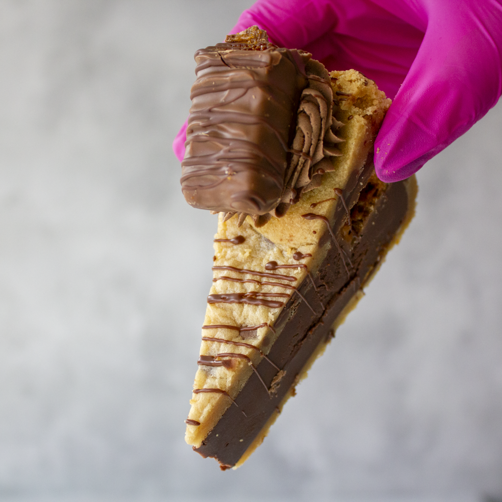 Cookie Pie Slice with Crunchie held in pink glove showing golden cookie pie base