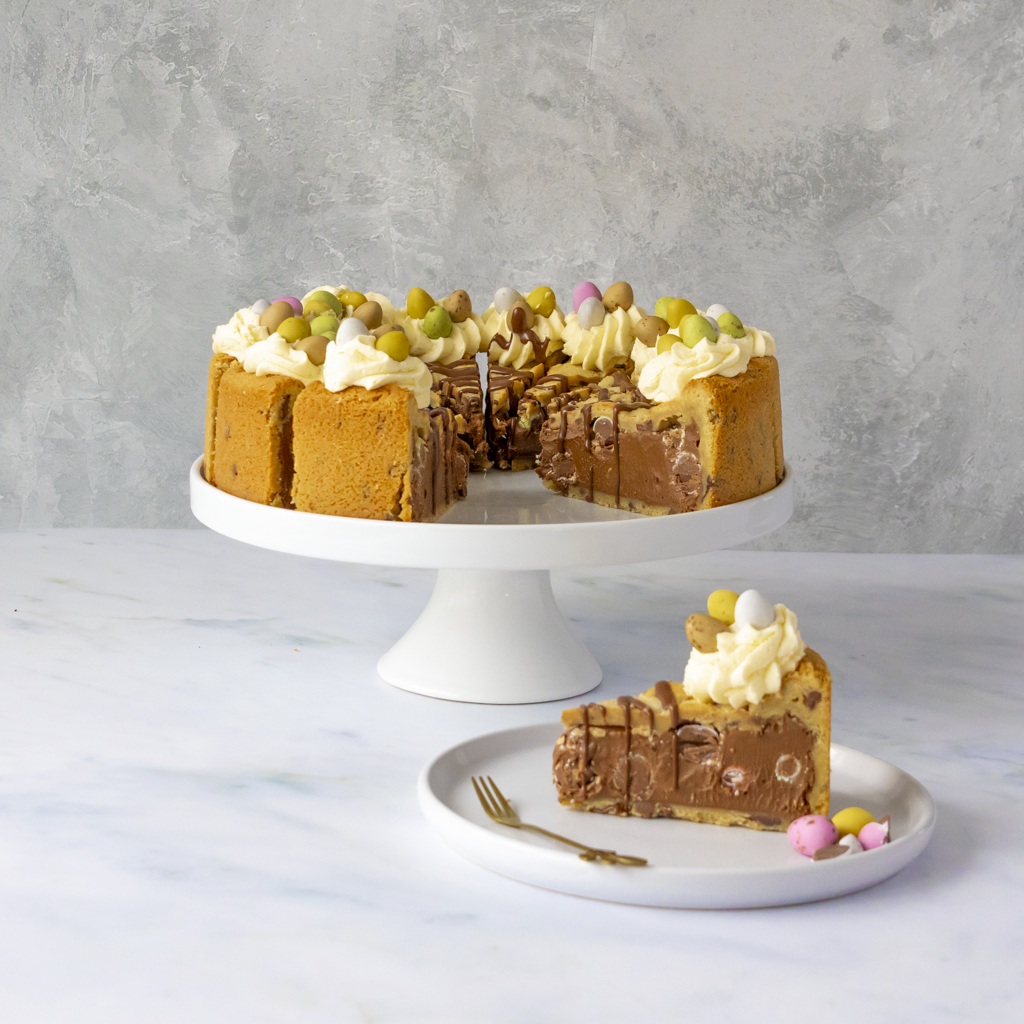 Chocolate Easter egg cookie pie with Easter Mini Eggs decorations on a white cake stand against a gray background