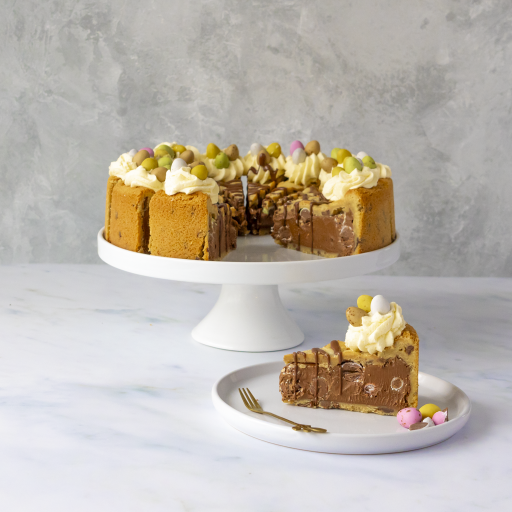 Chocolate mini egg cookie pie with a slice on a plate against a gray background