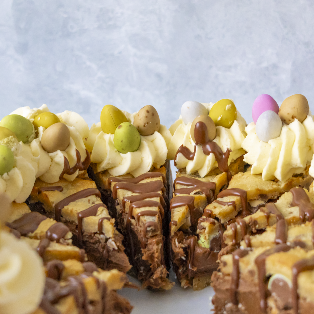 Close-up of a chocolate and Mini Eggs cake with Easter-themed decorations on a light blue background