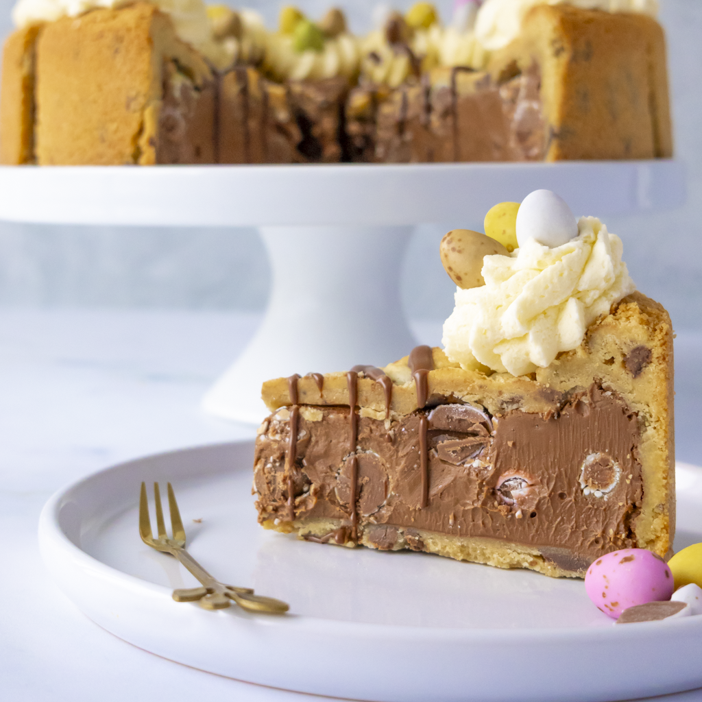 Slice of Mini Egg Cookie Pie by DoughGirl with whipped cream and Easter eggs on a white plate.