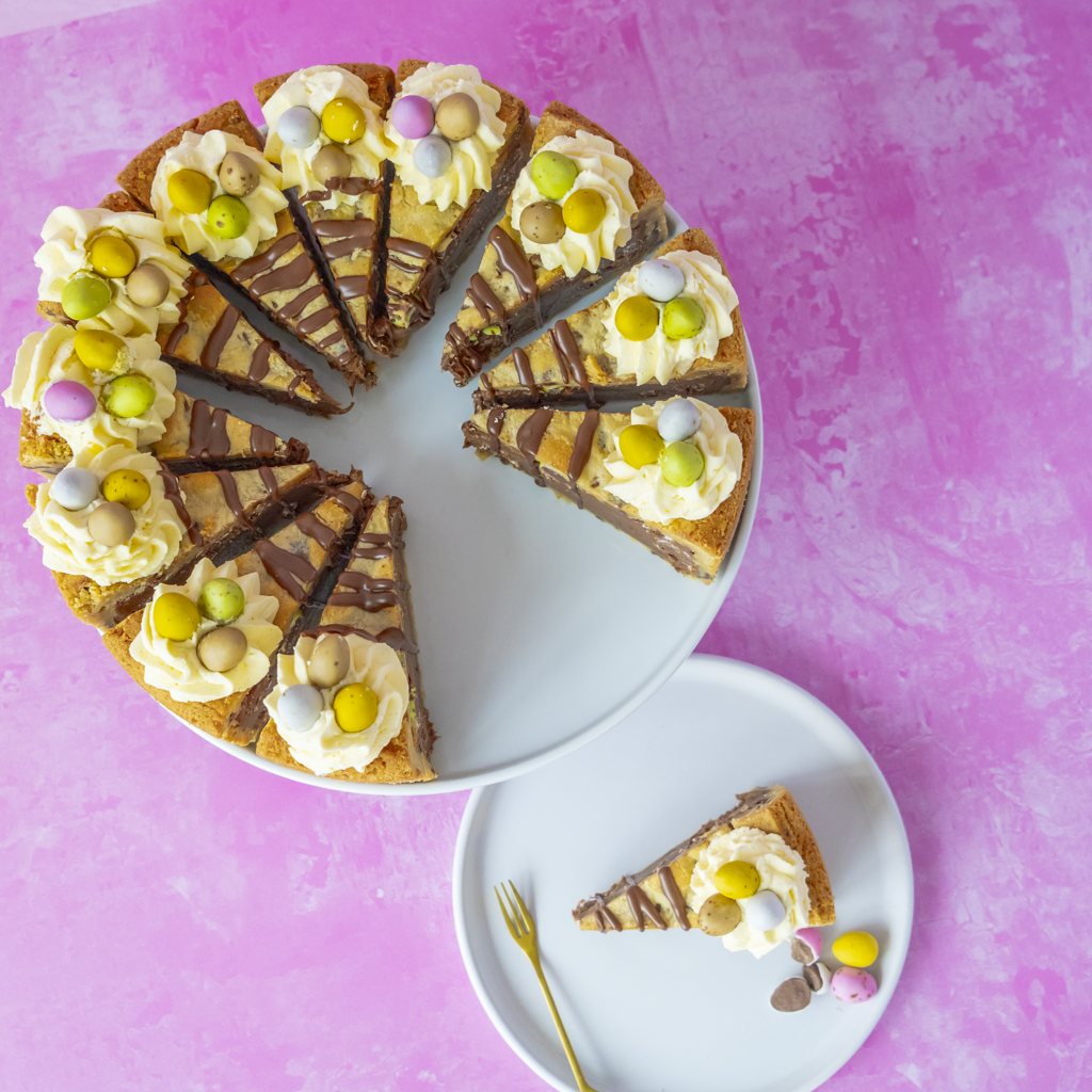 Chocolate cake with white frosting and colorful mini egg chocolate on a pink background
